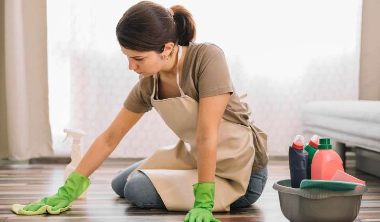 Woman in green glove cleaning floor with a cloth