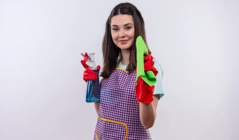 Woman in red gloves holding a spray bottle and a green cloth in her hand.