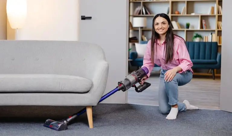 Lady is cleaning carpet with a vacuum cleaner.