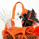 Gift box and paper ghost and bat in shopping bag on white background top view
