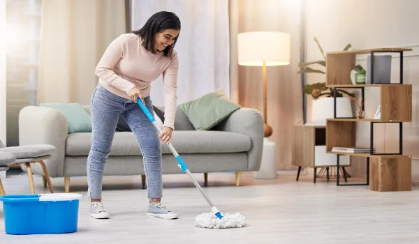 Happy woman and cleaning floor in home with mop for hygiene with detergent for safety