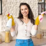 Domestic chores portrait of happy housewife holding spray bottle and microfiber cloth smiling at
