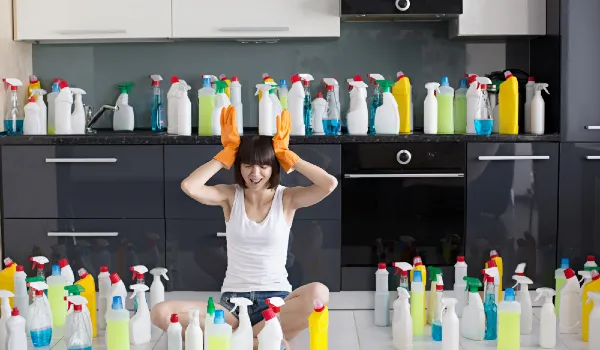Beautiful young woman makes cleaning the house and lots of cleaning products around her